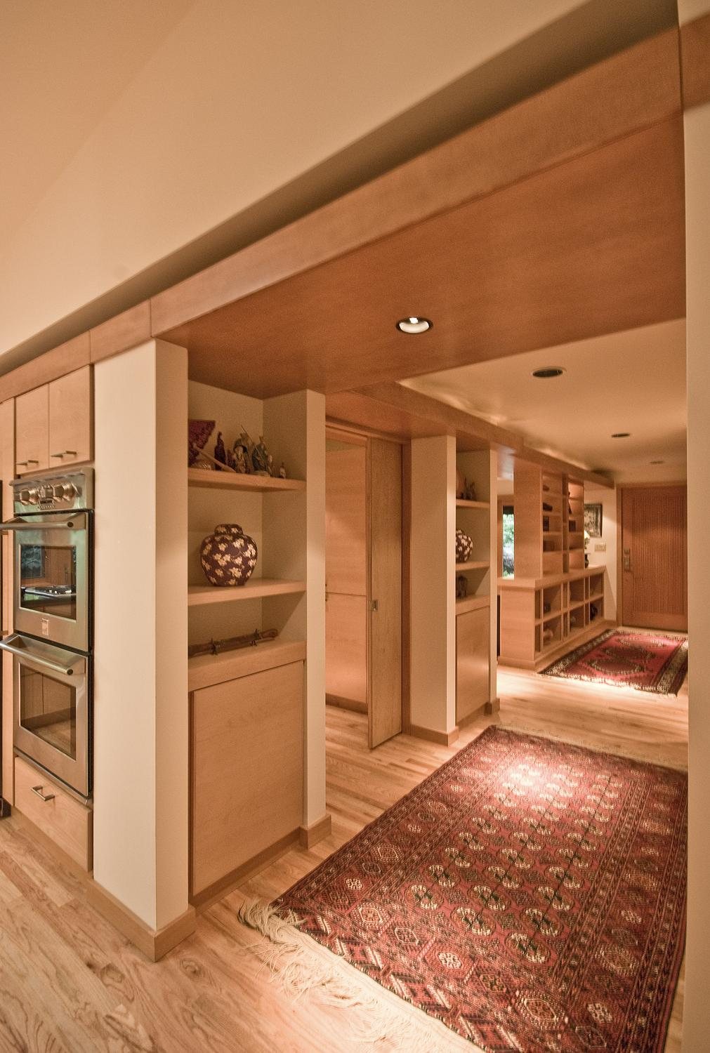 Blonde wood custom cabinetry with built-in shelving and double oven
