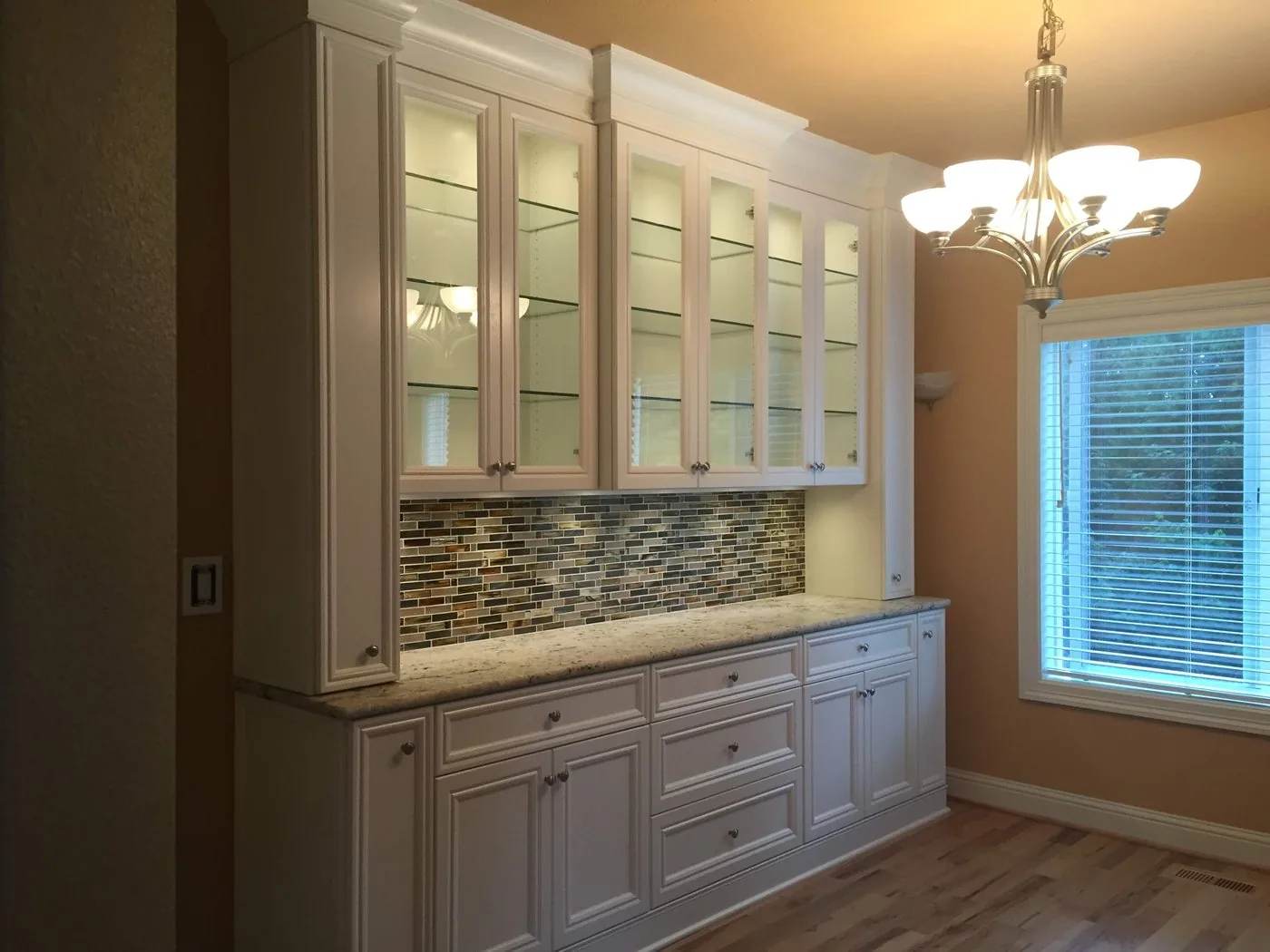 Built-in cabinet unit with glass uppers and a tiled backsplash, built by KDJ Cabinet Design